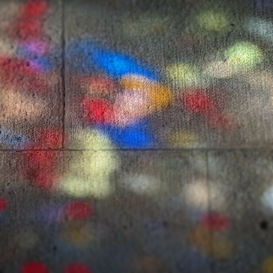 Blurred coloured spots of light cast onto a concrete wall