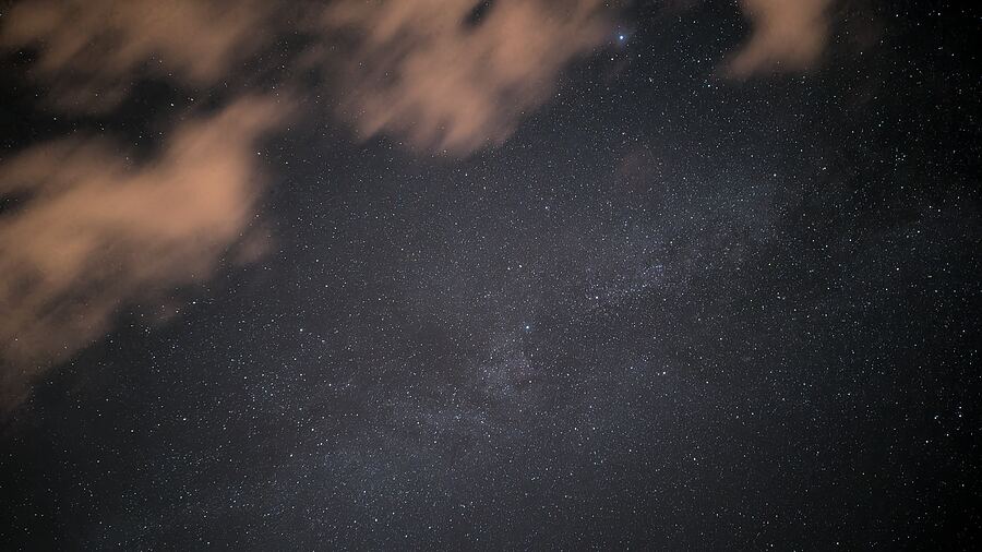 The Milky Way behind a few lit-up clouds