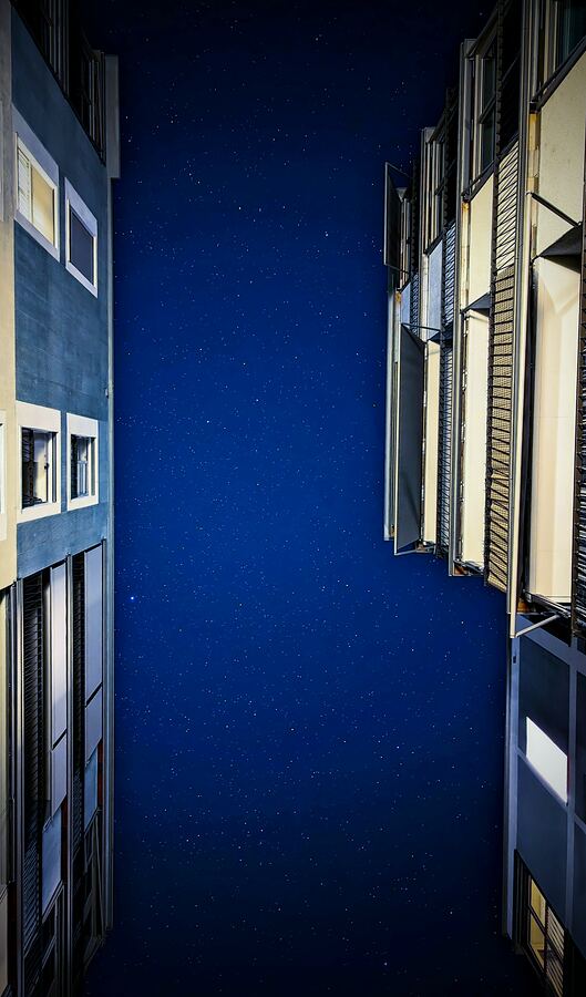 Deep blue night sky framed by the walls of a narrow alley