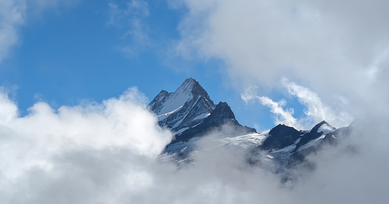 A sharp snow-covered peak emerging from thick cloud